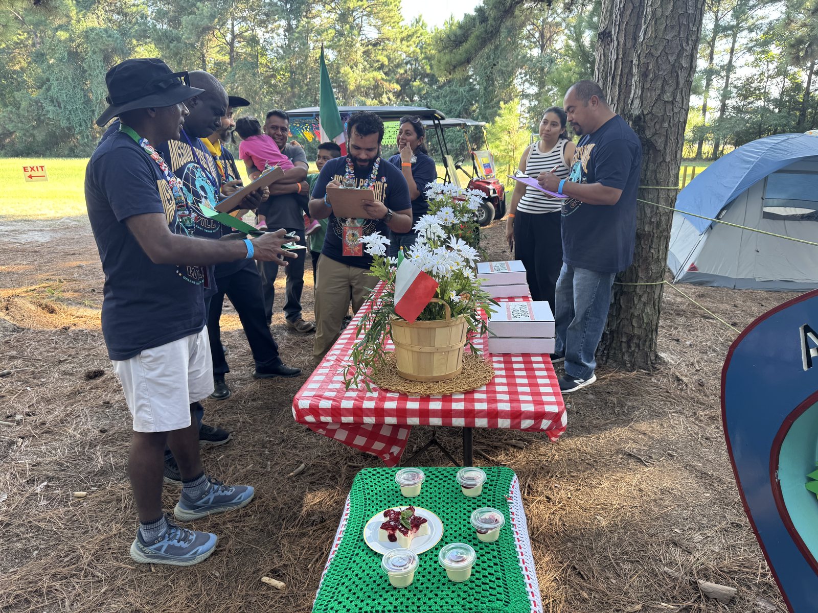 Judges with clipboards tasting dishes at a decorated campsite table during Ultimate Adventurer Chef