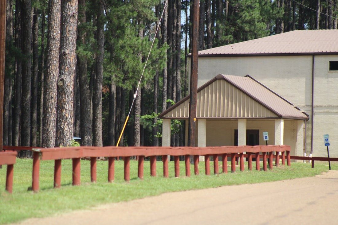 The outside of the Lone Star Camp gymnasium among the pines